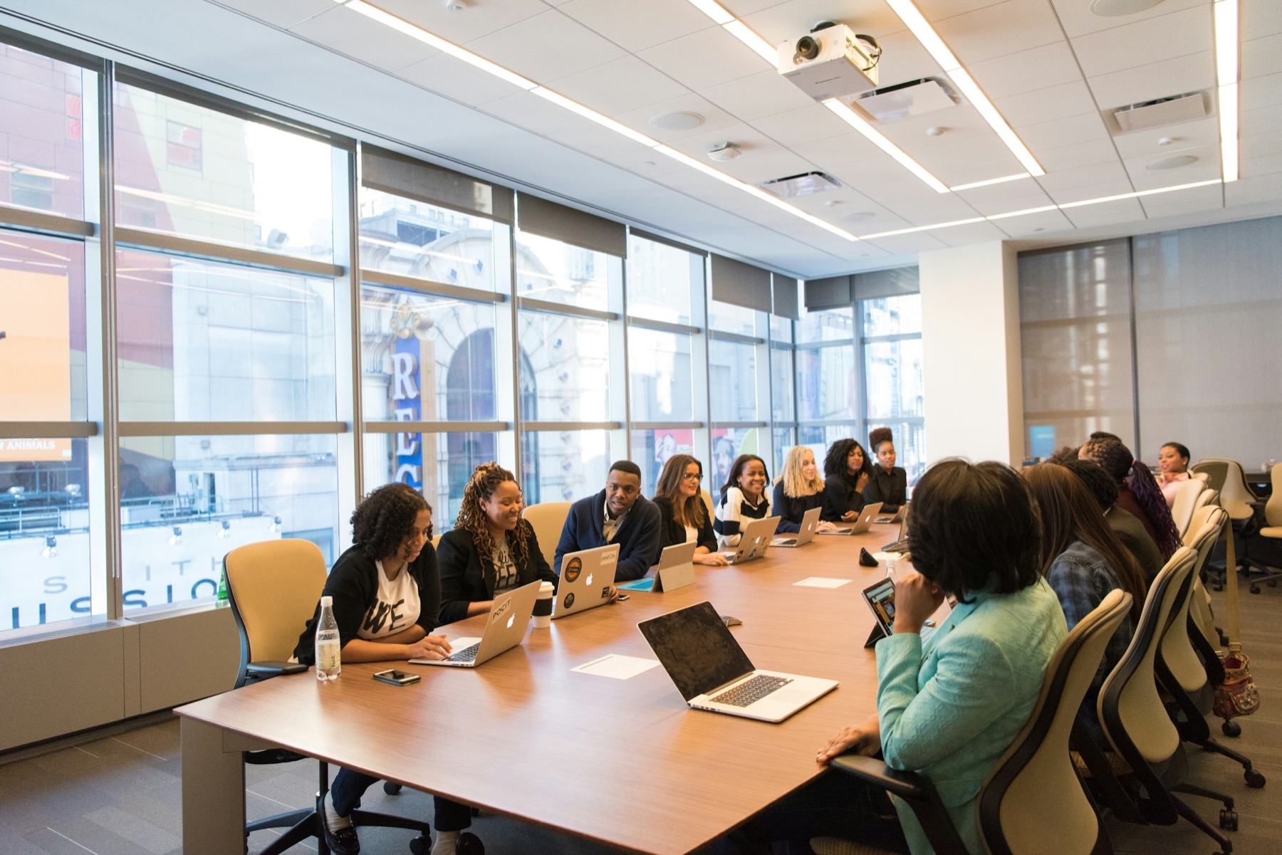 A room of staff with laptops around a long table